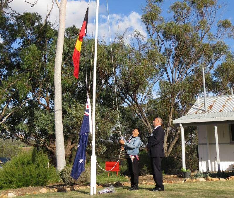 Official: Claire McGuire, who gave the welcome to country, hoists the Aboriginal flag as Fresh Start chief executive Jeff Claughton looks on. Mr Claughton raised the Australian flag earlier as a reminder for people to be good citizens. 