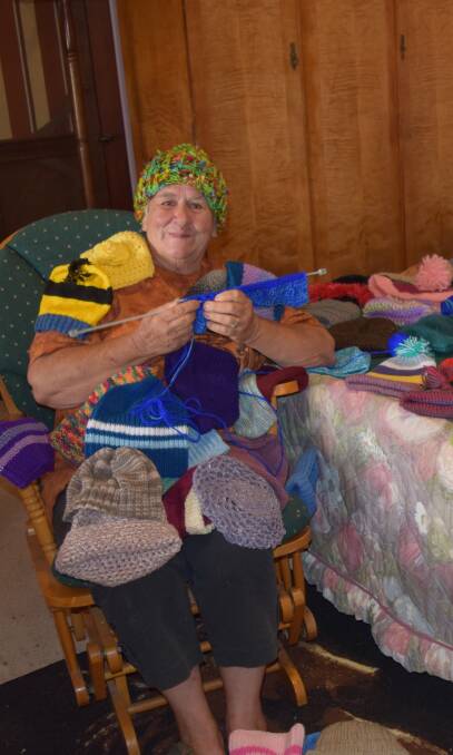 Karen Ducat adorned with dozens of beanies that have been donated to Comfort Quilts by people within the community. 