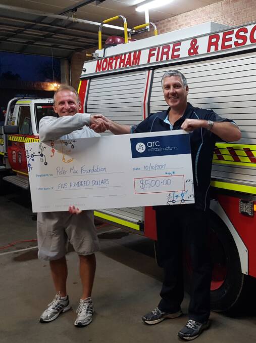 Canadian cancer survivor Rudy Pospisil with Northam Volunteer Fire and Rescue Captain Scott Horlin, holding a $500 cheque donated by Arc Infrastructure, at the event on Tuesday October 11. 