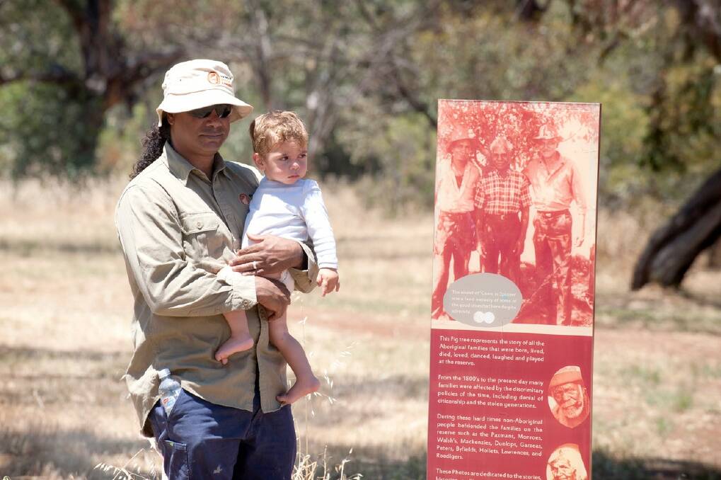 Wheatbelt Natural Resource Management Nyoongar Boodja ranger David Slater, holds his grandson as he views the newly erected signage at the Northam Reserve.