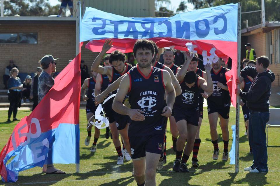 Fantastic achievement: Cameron Lawler bursts through the banner to play in his 150th game for the Federals Football Club. Photo: supplied.